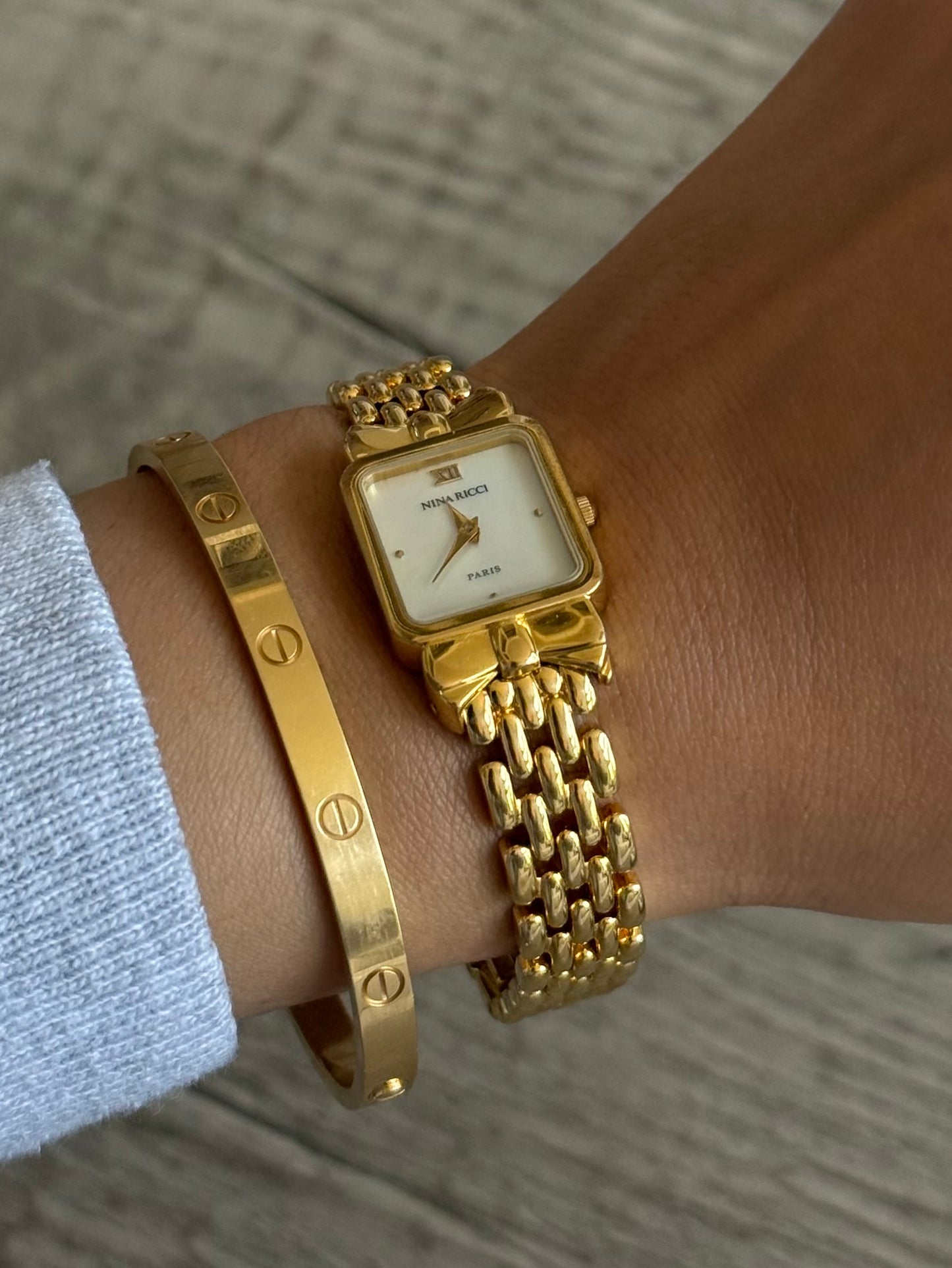 Nina Ricci Gold Toned Watch with Bow Bezel Set